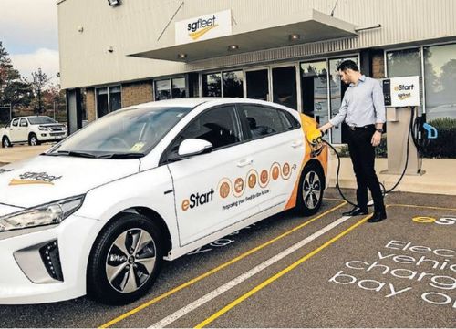 A man connects a charger to an SG fleet electric vehicle