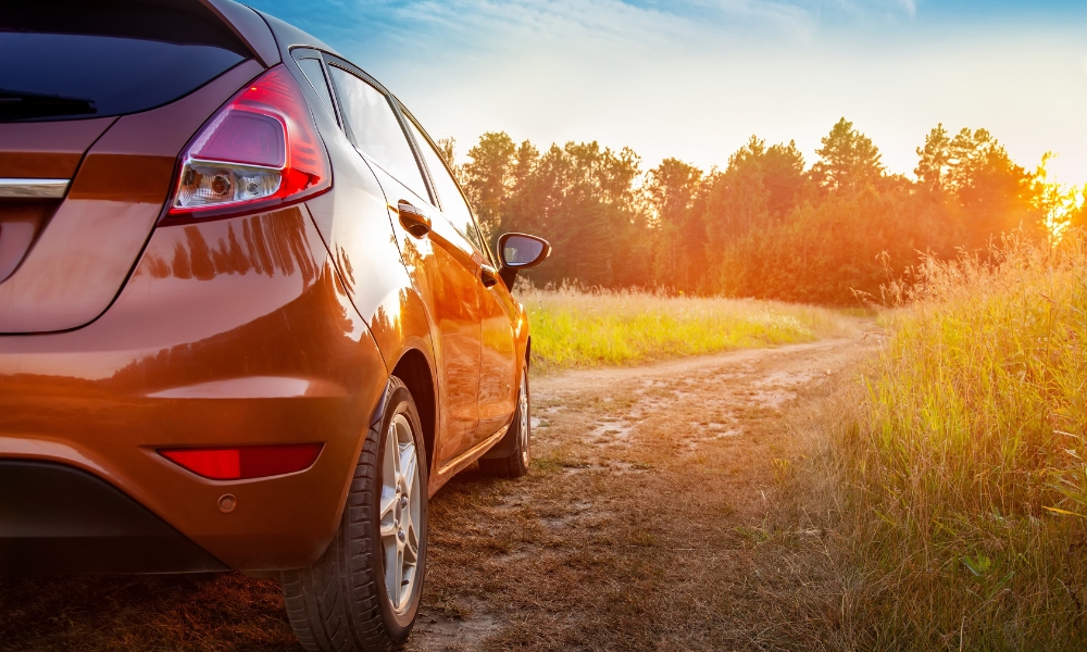 An orange lease car in a rural setting at sunset