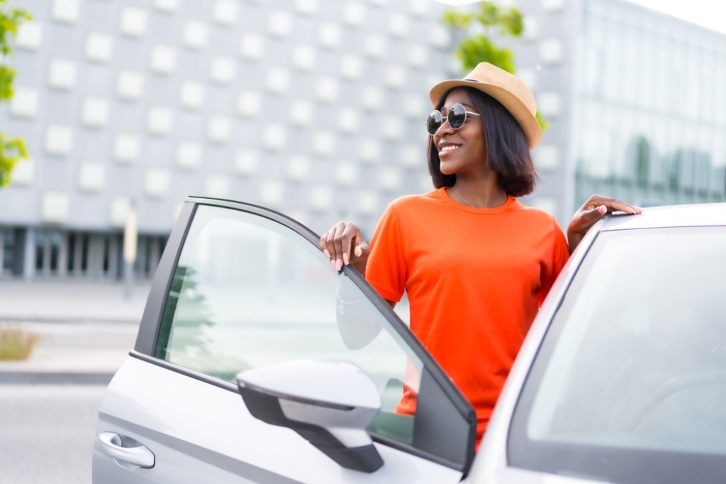 A woman in an orange top gets out of a salary sacrifice car.